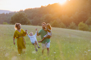 Happy young family spending time together outside in green nature.