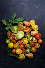 Colorful cherry tomatoes texture closeup on black background, selective focus