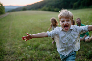 Happy young family spending time together outside in green meadow, little boy running and enjoying...