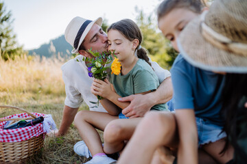 Fototapeta premium Happy father and his daughter hugging together, celebrating birthday during family picnic in nature.