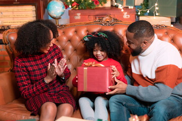 Father, mother and child family rejoicing in the joy of opening a gift box on Christmas Day.