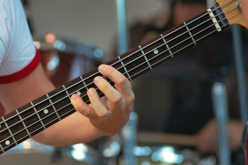 Fototapeta premium Fingers on strings of an electric bass guitar