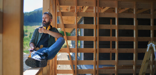 Handyman resting and having break when working on wooden construction site, diy eco-friendly homes concept.
