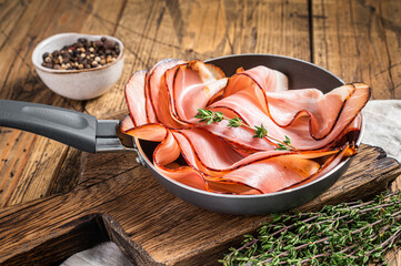 Thinly sliced German Black Forest Ham bacon in skillet. Wooden background. Top view