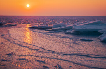 Sunrise and frozen sea. Beautiful winter landscape with lake and red sun in morning time. Daybreak