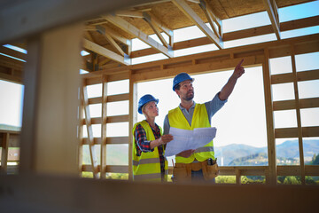 Construction engineers or architects with blueprints visiting and chcecking eco building site of...