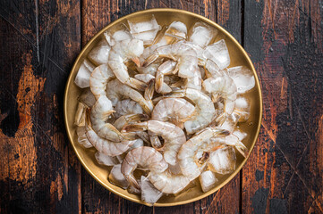 Fresh Raw tiger white shrimp prawn peeled with tail on ice. Wooden background. Top view