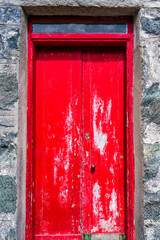 Weathered red wooden front door in old stone building