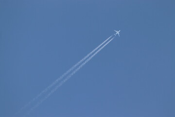 an airplane flying in the blue sky and leaving a line