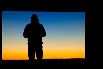 Fototapeta premium Silhouette of a person on the background of a yellow-blue sky.