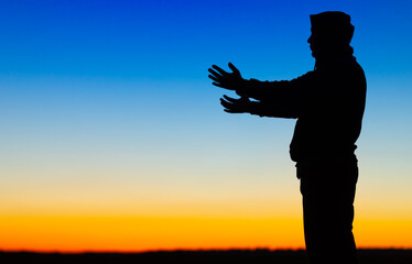 Silhouette of a person on the background of a yellow-blue sky.
