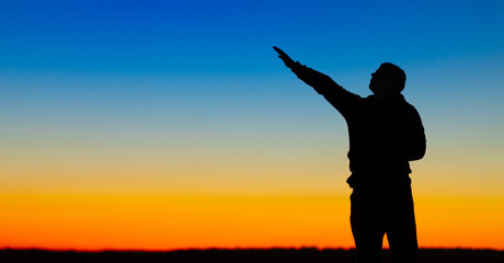Fototapeta premium Silhouette of a person on the background of a yellow-blue sky.