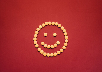 Medical pills are laid out on the table in the shape of a smiling face.