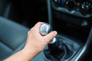 Closeup hand of a driver at the gear knob when going to change the manual gear shift in the car