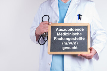 Arzt mit einer Tafel auf der Auszubildende Medizinische Fachangestellt m/w/d gesucht