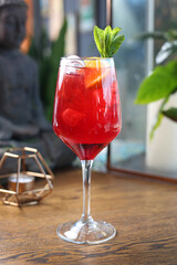 Red cocktail, spritz, drink in a glass, with ice cubes and orange slice, on a wooden table, selective focus.