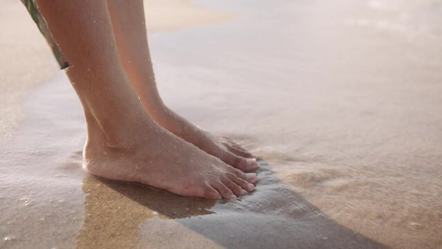 Close-up of young biracial woman barefoot in sea by beach