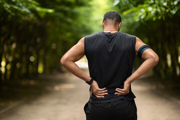 Back view of sportsman touching sore zone on his back