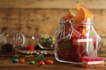 Delicious jelly candies in jar on wooden table, closeup. Space for text