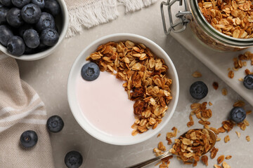 Delicious yogurt with granola and blueberries served on grey marble table, flat lay