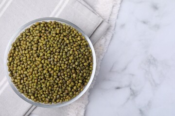Glass bowl with green mung beans on white marble table, top view. Space for text