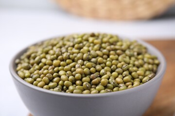 Bowl with green mung beans on white table, closeup