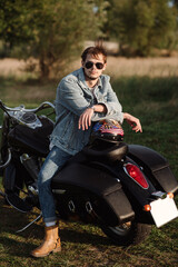 Fototapeta premium Handsome male biker wearing a jeans clothes is sitting on the motor bike