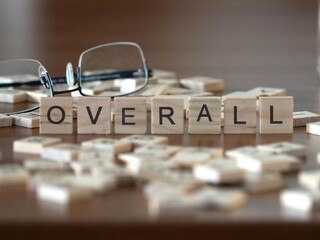 overall word or concept represented by wooden letter tiles on a wooden table with glasses and a book