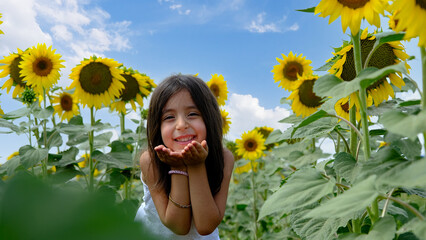 Girl smiling and playing in a field of sunflowers.