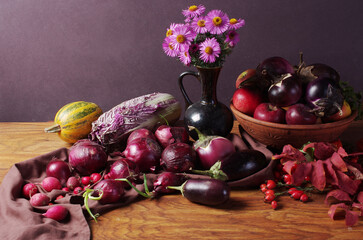 Vegetables eggplant, red onion, red cabbage, autumn flowers on a wooden table.