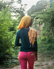 Back of young black african woman walking in a peaceful path in nature. Sunset light. Concept of relaxing activity. 