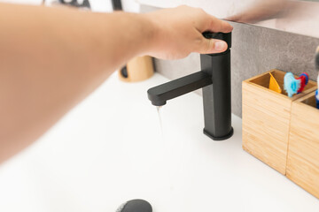 man's hand opening the sink faucet water in the bathroom