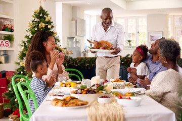 Multi-Generation Family Celebrating Christmas At Home With Grandfather Serving Turkey