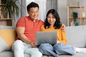 Fototapeta premium Asian lovers watching movie on Internet, using laptop
