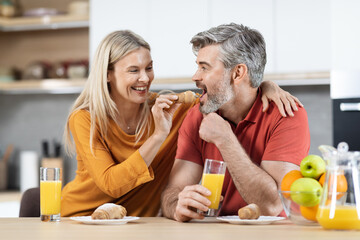 Positive blonde woman feeding her handsome spouse