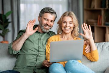 Happy Middle Aged Couple Making Video Call With Laptop At Home