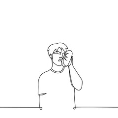 man put a small pillow to his cheek, he writhes in pain - one line drawing vector. concept comfort or pain relief