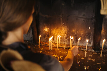 Orthodox church candles. Ritual of lighting candles in Eastern Europe. Girl in catholic cathedral....