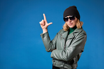 Young beautiful woman wearing casual jacket over isolated blue background. Shooting pointing hand and fingers up like gun