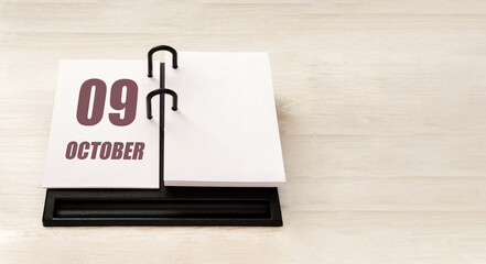 october 9. 9th day of month, calendar date. Stand for desktop calendar on beige wooden background....