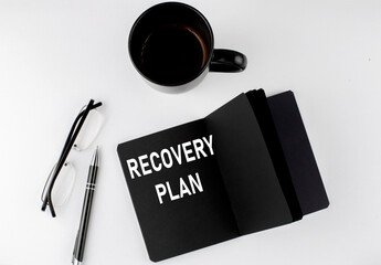 Naklejka premium RECOVERY PLAN written text in small black notebook with coffee , pen and glasess on white background. Black-white style