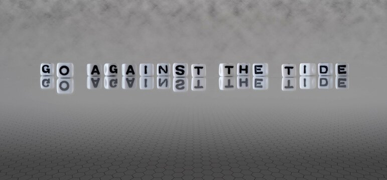 go against the tide word or concept represented by black and white letter cubes on a grey horizon background stretching to infinity