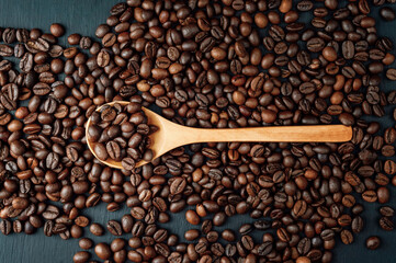 spoon with coffee on a black background.  spoon with coffee beans. coffee bean. Texture  of roasted coffee beans .