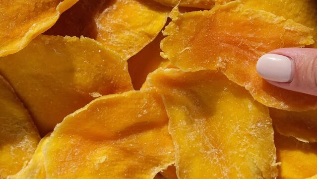 Dried mango slices close-up on a white. Top view. Closeup. Mango chips background. Dehydrated crispy fruit slices, pieces. Heap of sun-dried yellow fruit. Healthy meal. Top view, flat lay. 4K Footage.