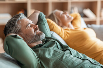 Smiling Middle Aged Couple Relaxing Together On Comfortable Sofa At Home