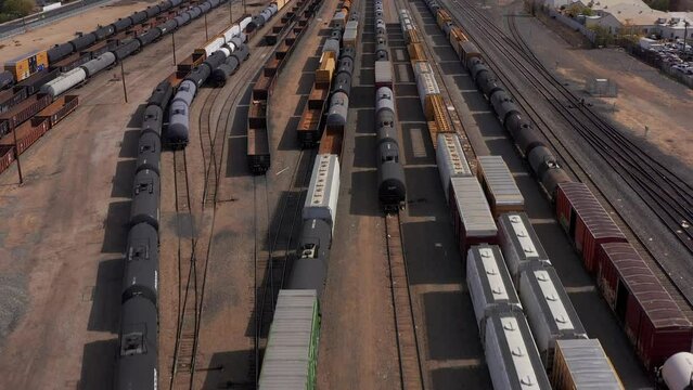Low tilting up aerial shot of rows of freight trains in an industrial railyard outside Bakersfield, California. 4K