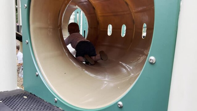 Toddler crawling in playground tunnel.