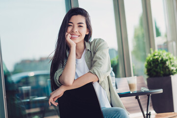 Fototapeta premium Photo of shiny dreamy girlfriend wear green outfit sitting cafe smiling outdoors city residential complex