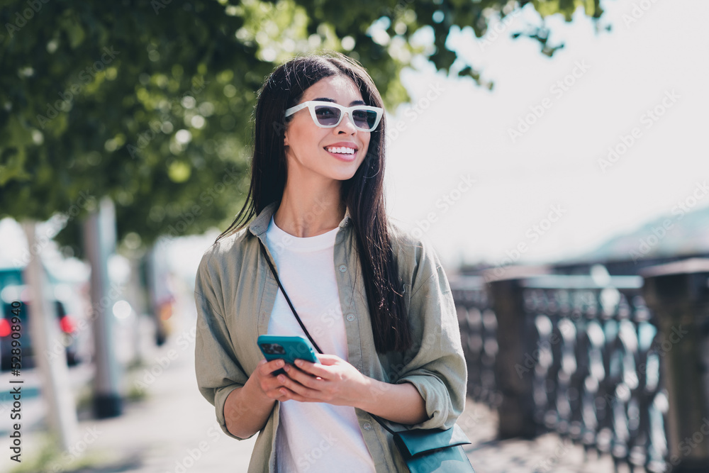 Wall mural photo of sweet dreamy lady dressed casual clothes dark glasses walking chatting modern gadget sunshi