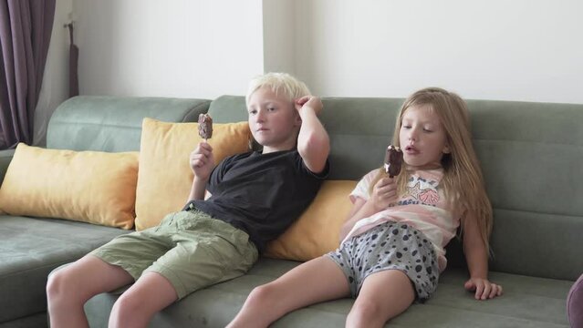 Cute boy and girl enjoy delicious ice cream at home.